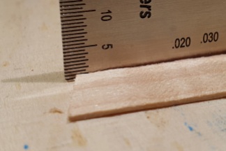 A piece of veneer on the workbench; a string action gauge shows the thickness of the material, roughly 1 mm
